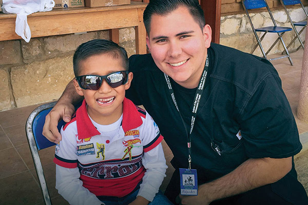 UIW Student on mission trip smiling next to child