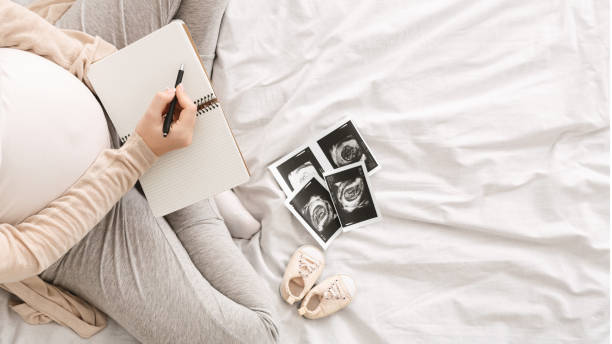 Women sitting on a bed with a notebook and ultrasound images of fetus