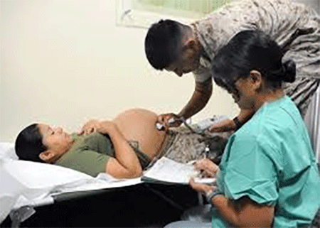 A military member checking pregnant women using stethoscope