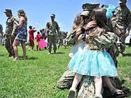 A military family embracing each other at a park